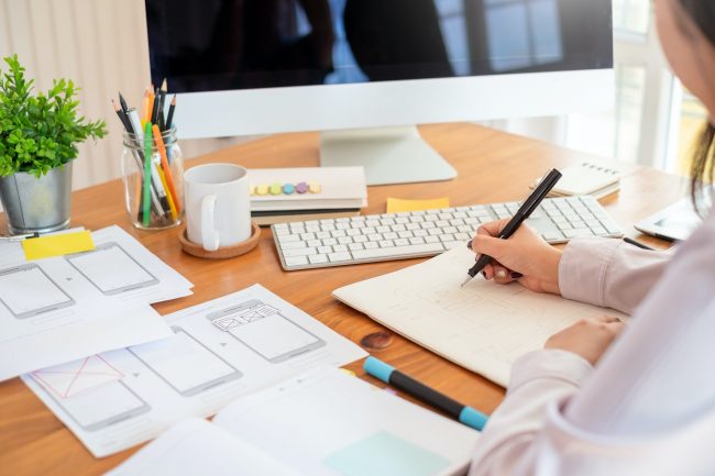 Designer woman drawing a website outline and website ux app development on mobile phone.